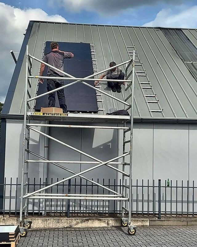 Zonnepanelen worden op het metalen dak van een bedrijfspand gelegd